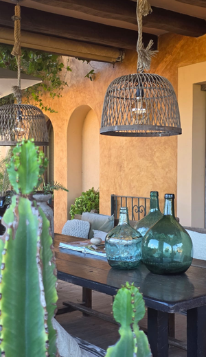 Terraza cubierta de Casa Naya Ibiza con lámparas de fibras naturales, mesa de madera y decoración artesanal.