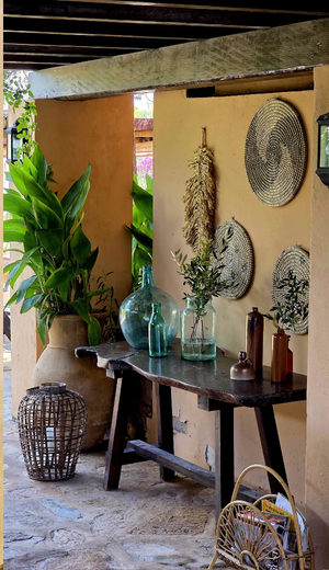 Rincón con estilo mediterráneo en Casa Naya Ibiza con consola de madera rústica, cestas decorativas y plantas tropicales