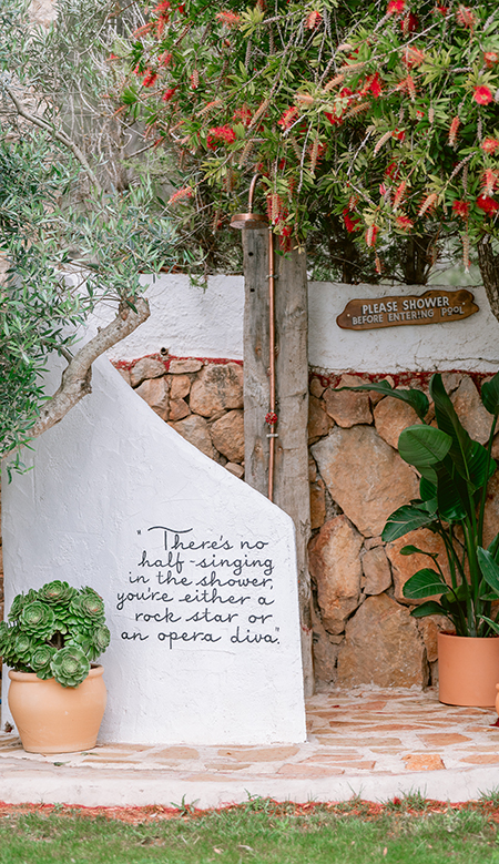 Terraza cubierta de Casa Naya Ibiza con lámparas de fibras naturales, mesa de madera y decoración artesanal.