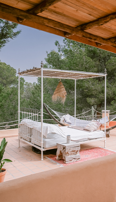 Rincón con estilo mediterráneo en Casa Naya Ibiza con consola de madera rústica, cestas decorativas y plantas tropicales