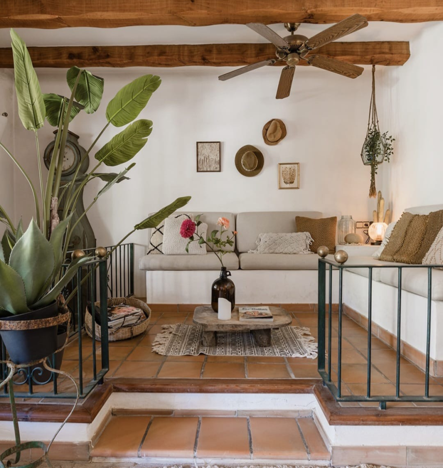 Salón acogedor de Casa Naya Ibiza con vigas de madera, decoración boho mediterránea y plantas tropicales