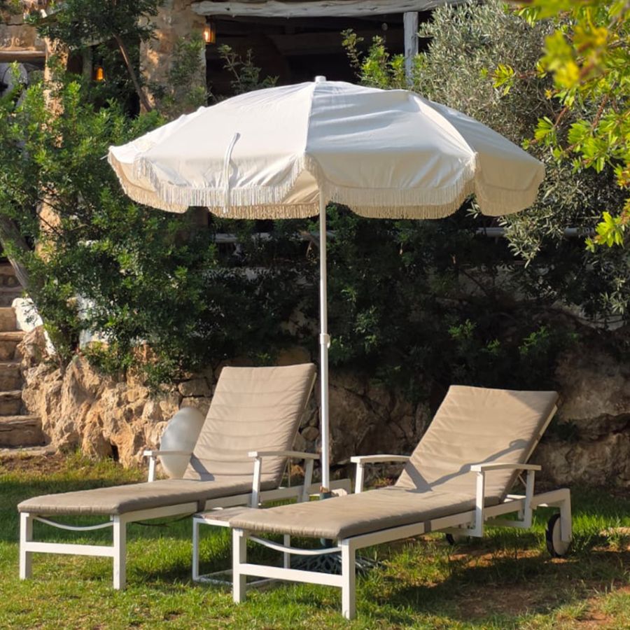 Zona lounge exterior de Casa Naya Ibiza con sofás de exterior, vegetación exuberante y vistas al jardín.